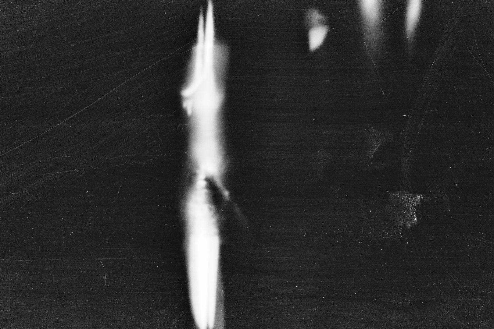 Schwarz-weiße Filmtextur mit hellem vertikalem Kratzer und Staubspuren